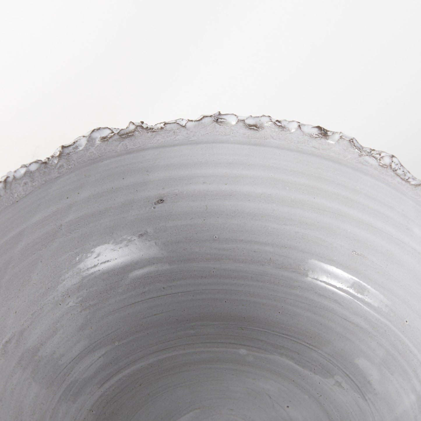 Gray white ceramic bowl showing unique artisan glaze where dark clay shows through creamy white finish