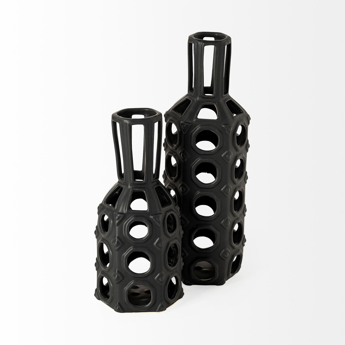 Close-up of circular cutouts and diamond details on black ceramic vase with metal wire top