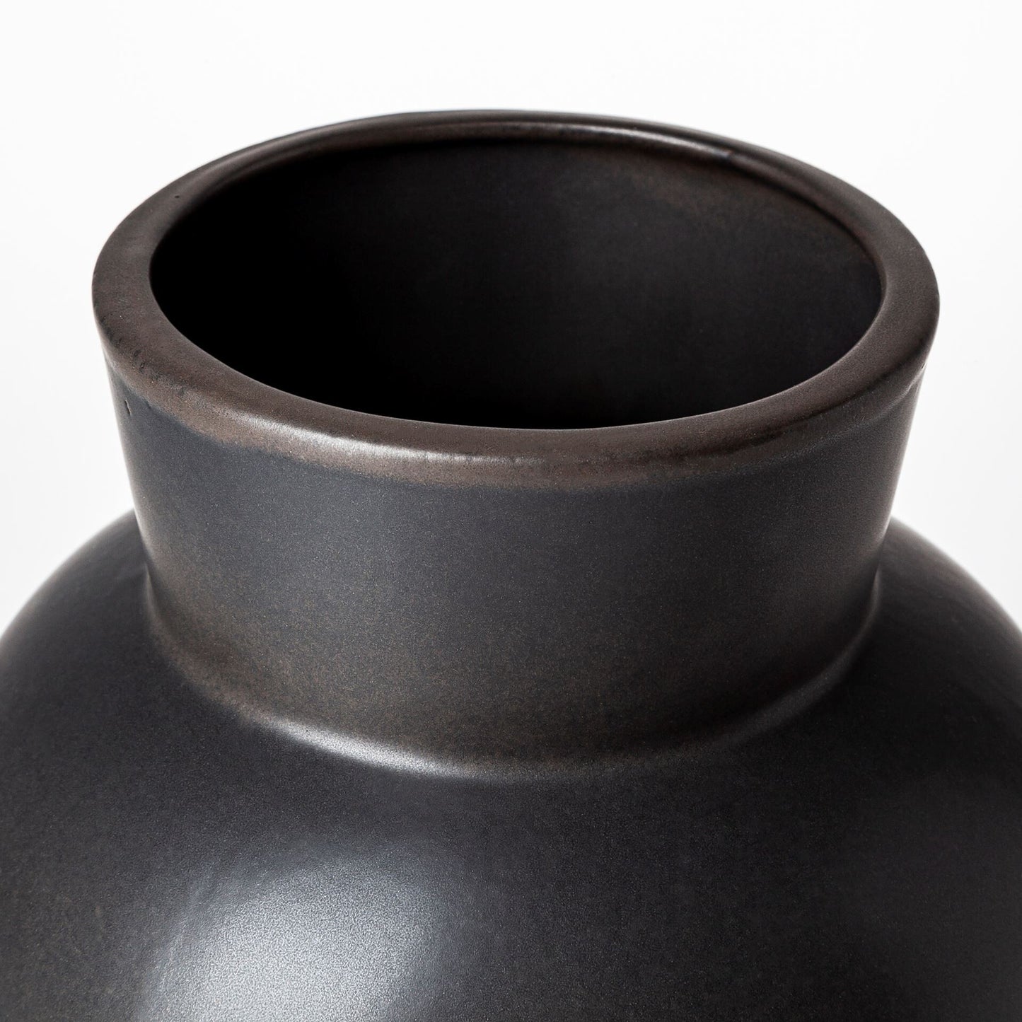 Close-up detail of matte black ceramic vase showing semi-matte finish and smooth curves of the circular body section, highlighting premium quality craftsmanship