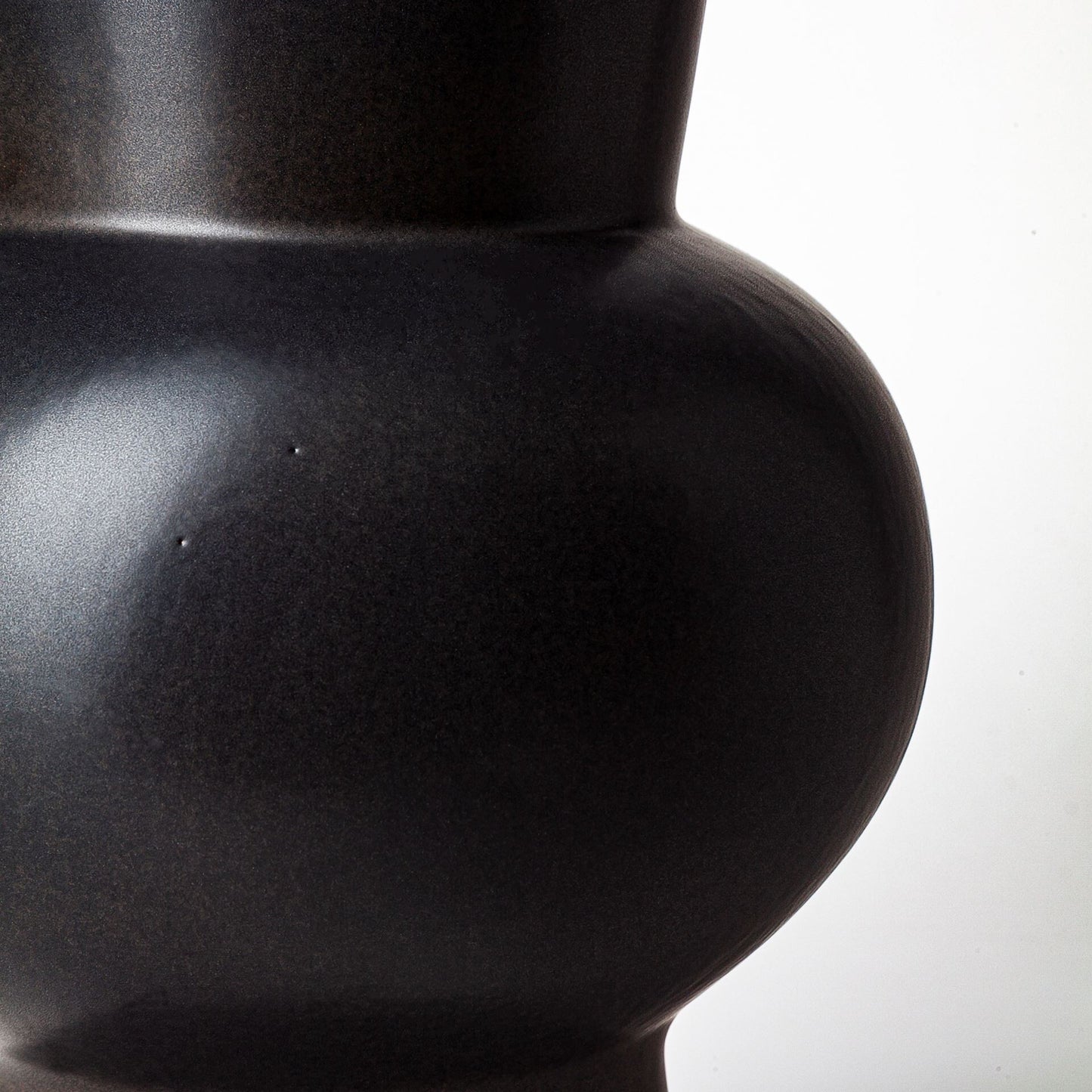 Three-quarter view of 11-inch matte black ceramic vase emphasizing unique architectural form and elegant proportions, ideal for living room or dining room decor