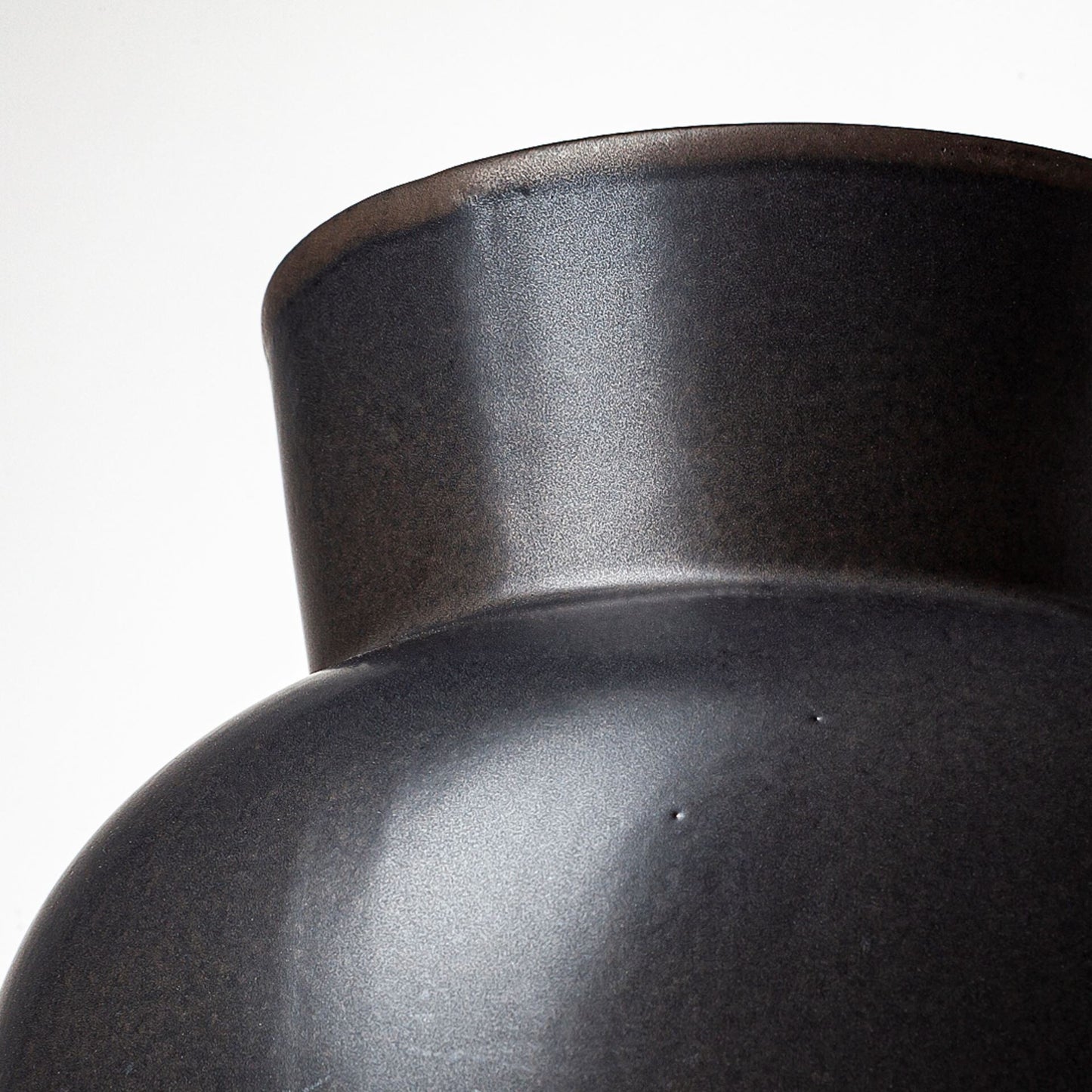 Three-quarter view of 11-inch matte black ceramic vase emphasizing unique architectural form and elegant proportions, ideal for living room or dining room decor