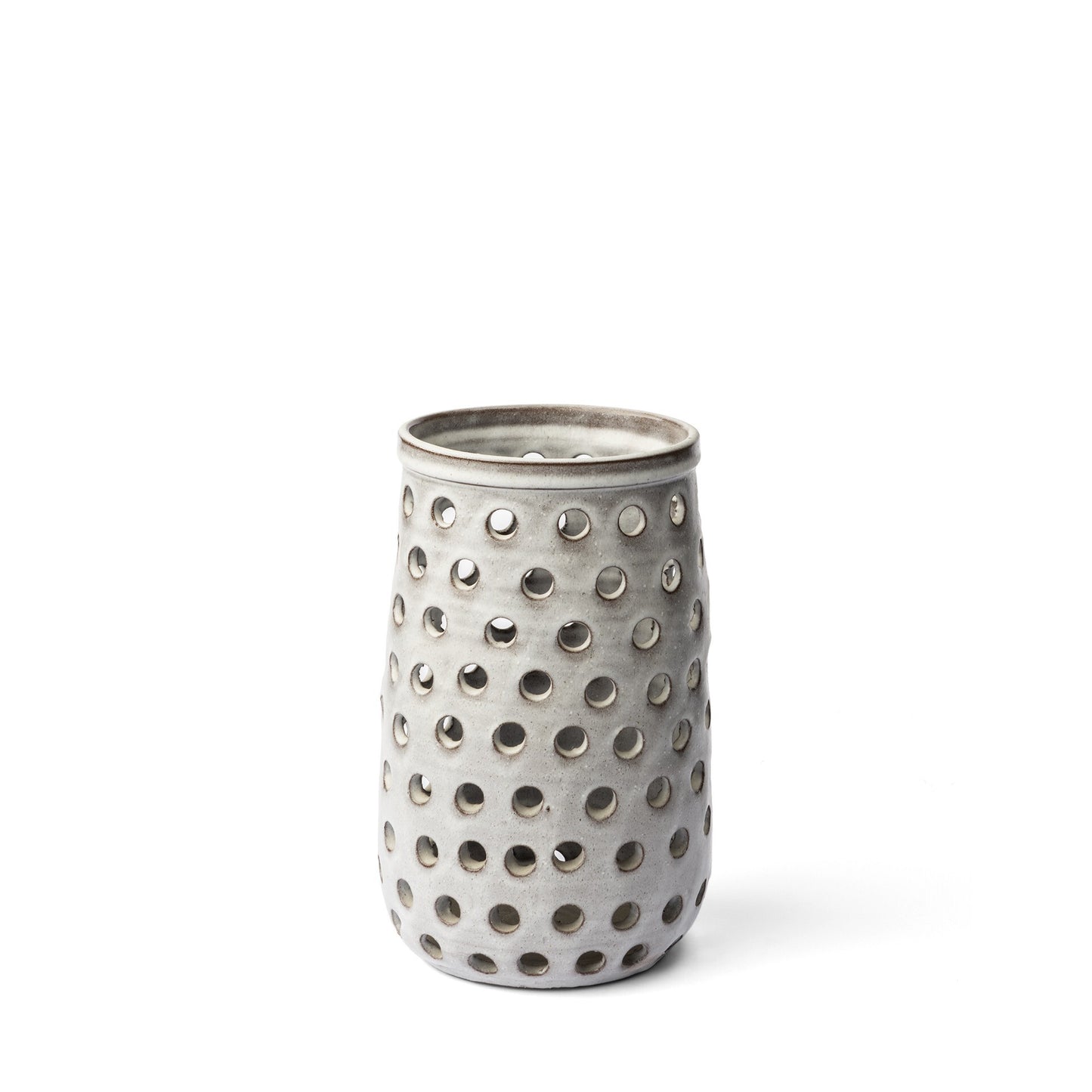 Close-up of handcrafted white ceramic vase showing intricate pierced circular perforations that create lightness and depth, ideal for modern contemporary interiors