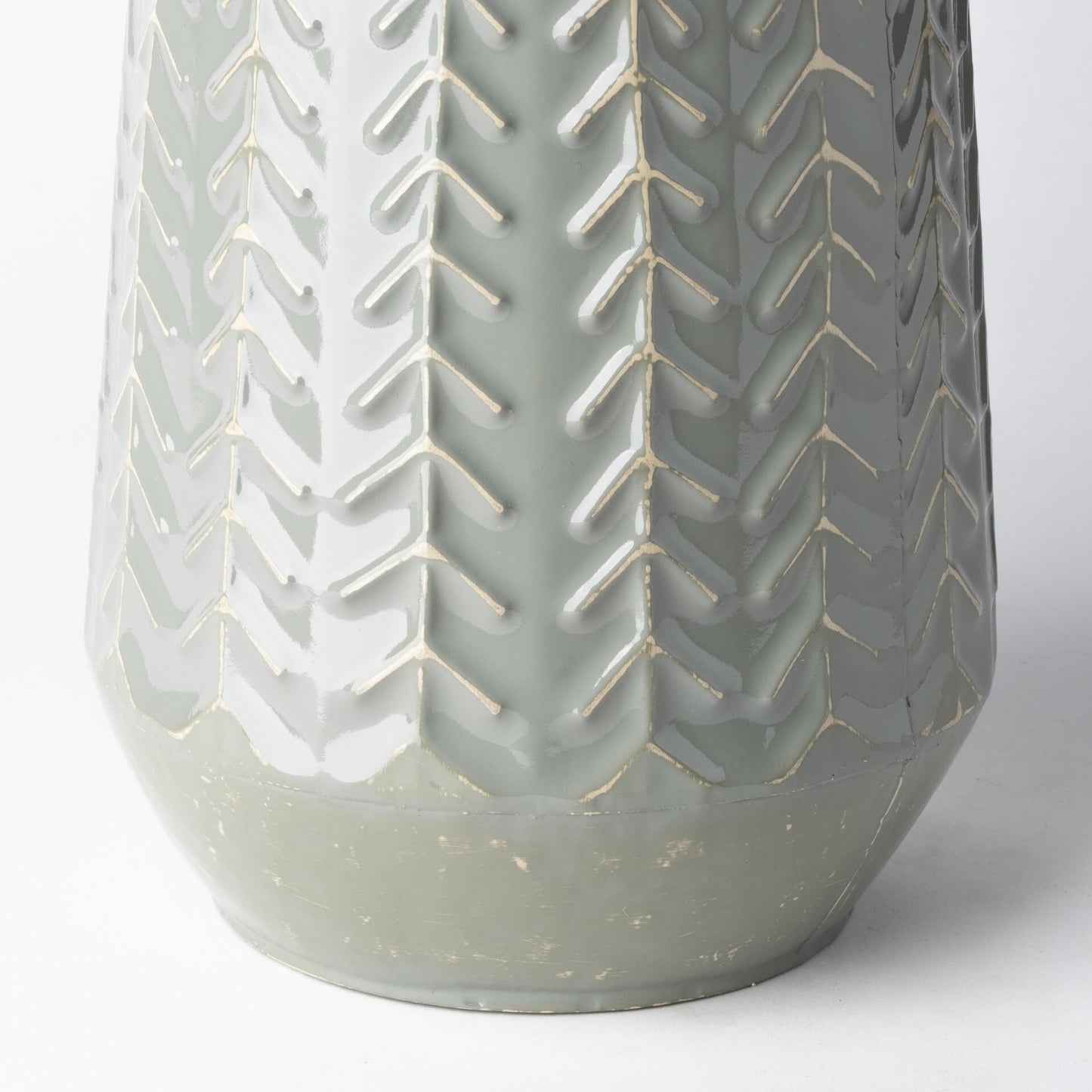 Embossed metal vase side view displaying chevron arrow pattern and solid metal construction