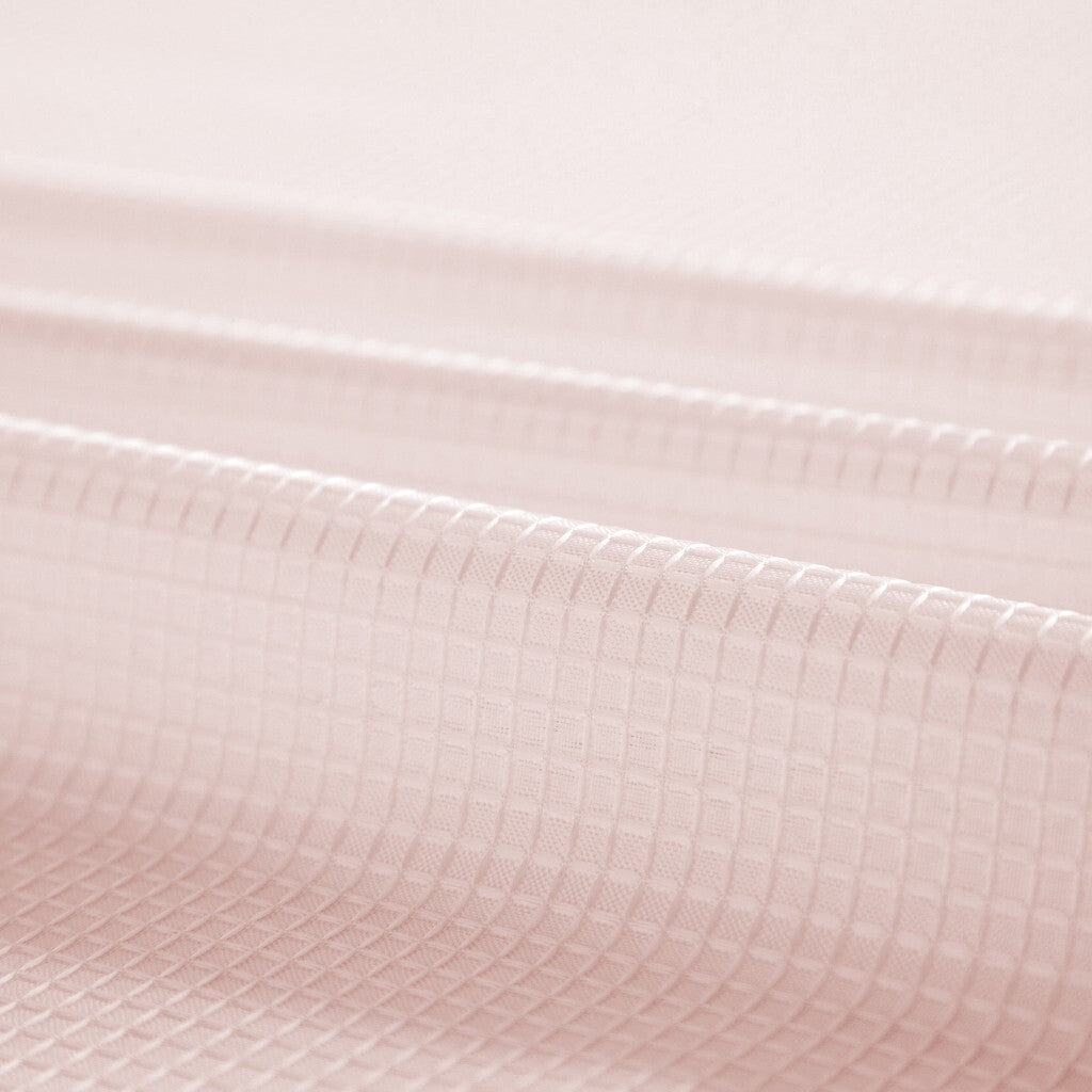Lifestyle image of blush pink grid shower curtain in modern bathroom with natural lighting