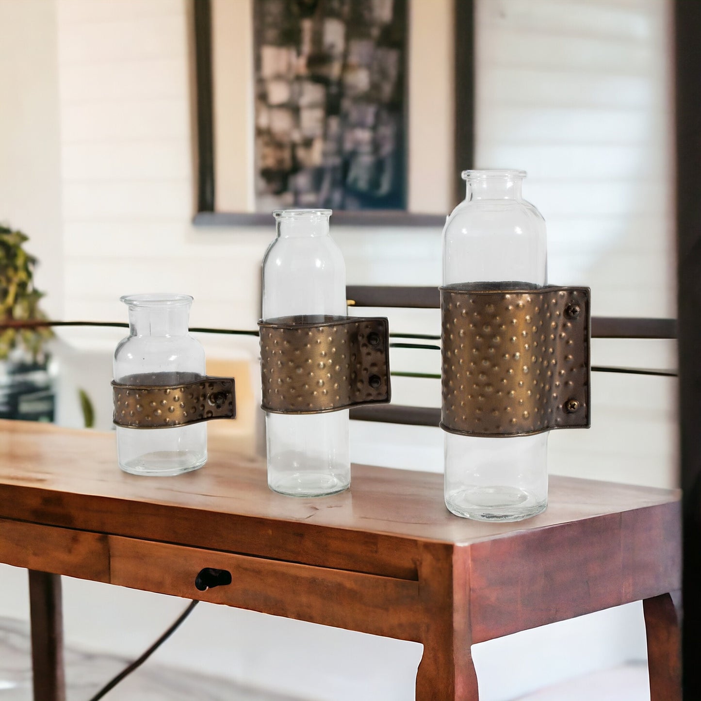 Close-up detail of hammered texture on bronze metal and clear glass cylinder vases showing premium construction and industrial charm