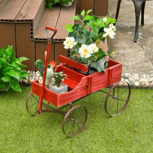 Red wooden garden cart planter on grass lawn with potted plants
