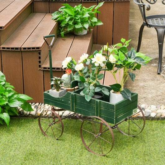 Green wooden wagon planter filled with herbs and small garden plants