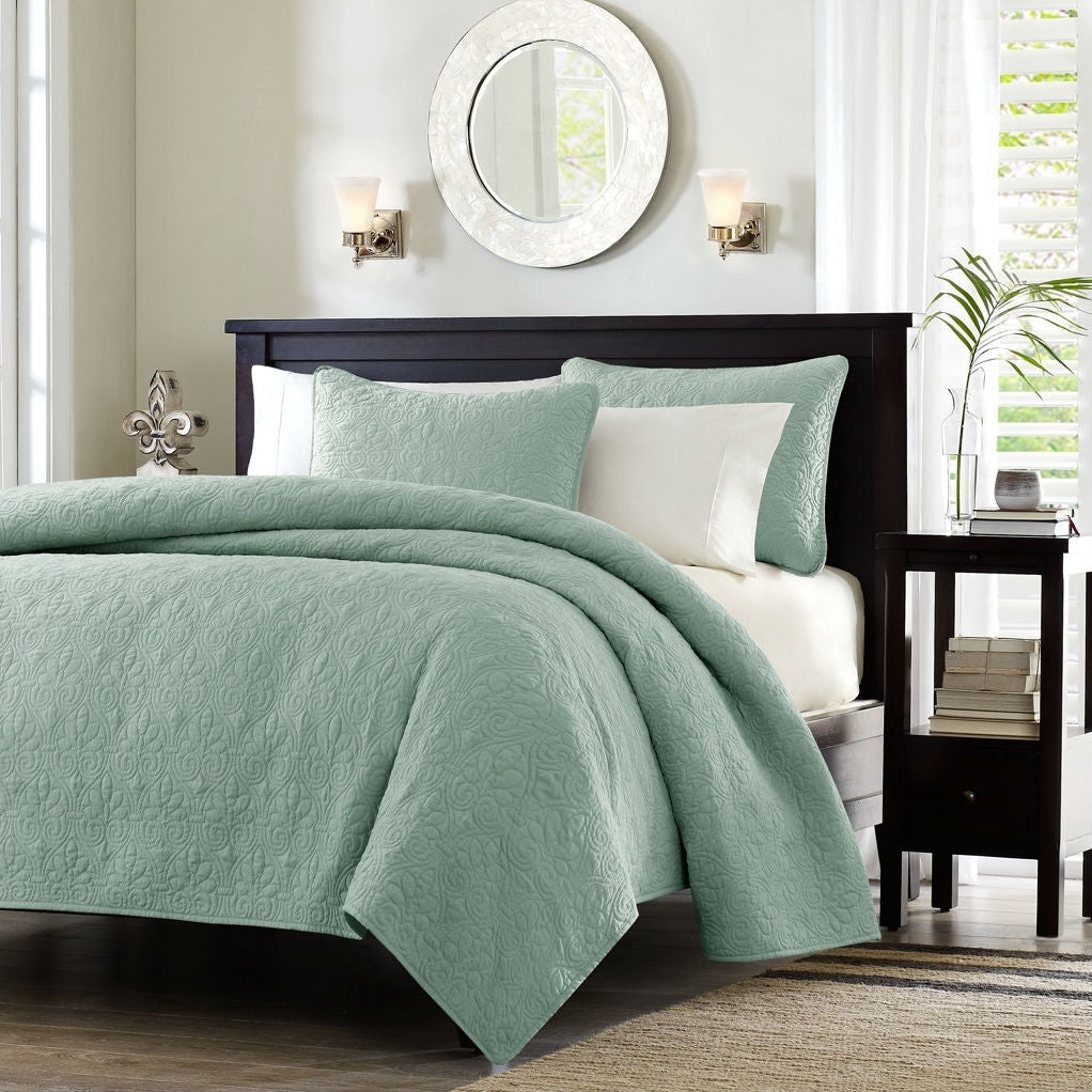 Close-up of seafoam blue quilted coverlet showing detailed floral quilting pattern
