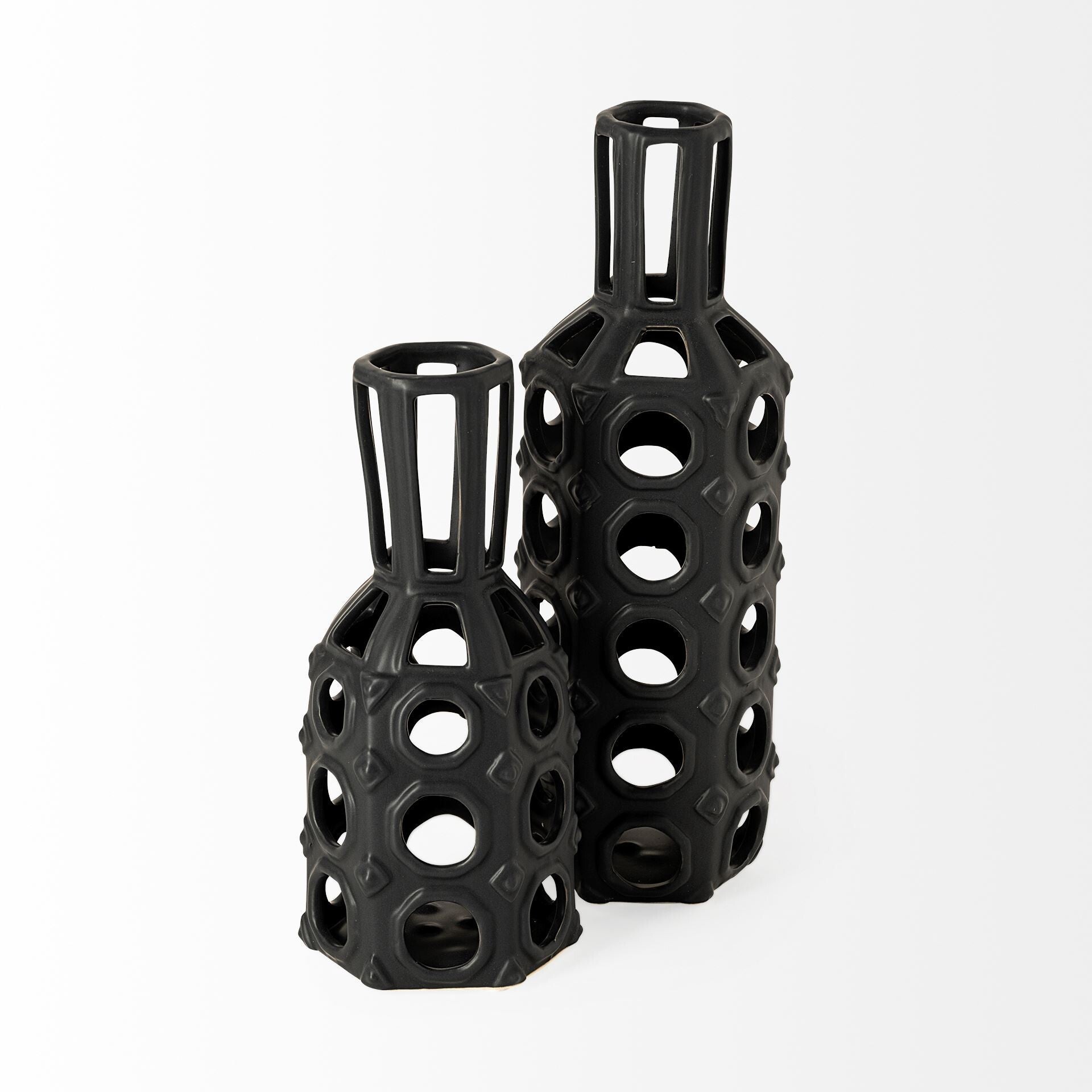 Close-up of circular cutouts and diamond details on black ceramic vase with metal wire top
