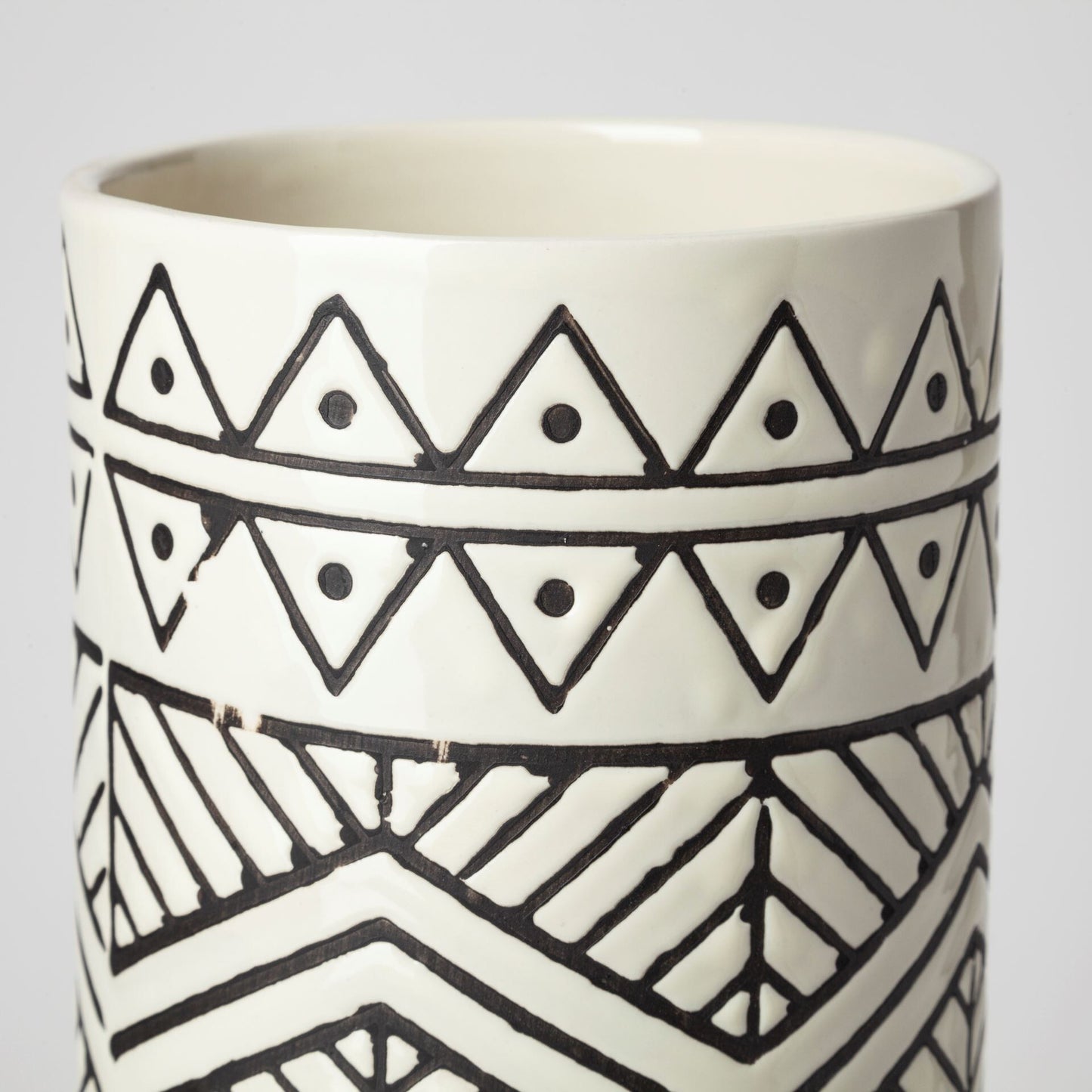 Detail of geometric pattern on cream ceramic vase showing modern minimalist design and textured surface
