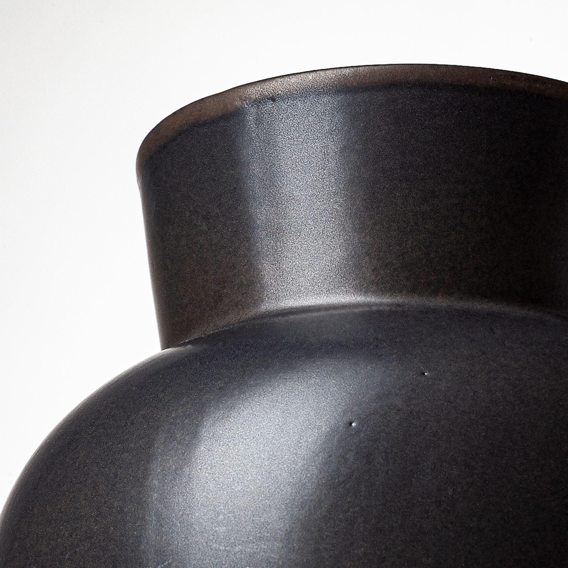 Three-quarter view of 11-inch matte black ceramic vase emphasizing unique architectural form and elegant proportions, ideal for living room or dining room decor
