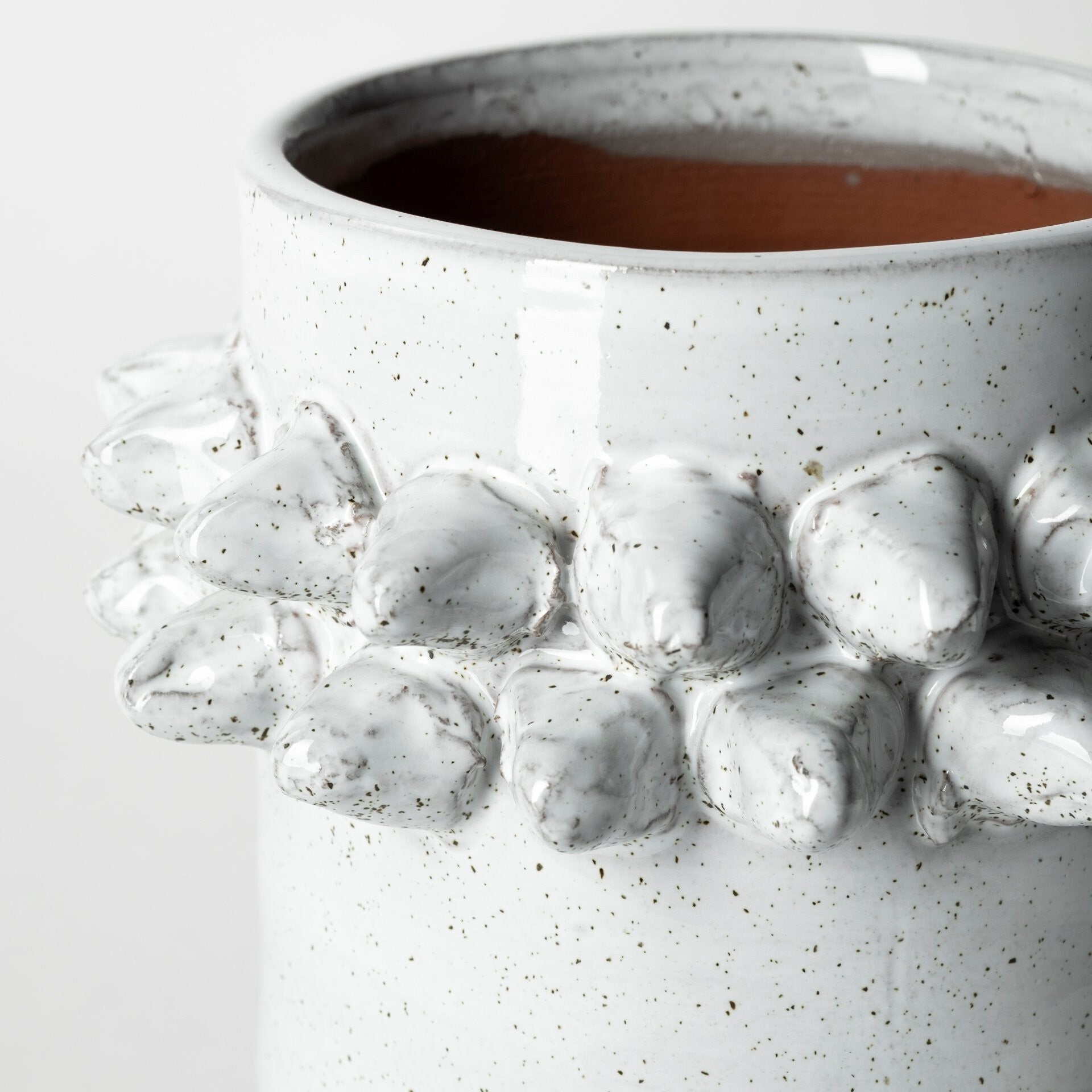 Close-up of organic speckled white glaze and 3D spikely detail on contemporary ceramic vase
