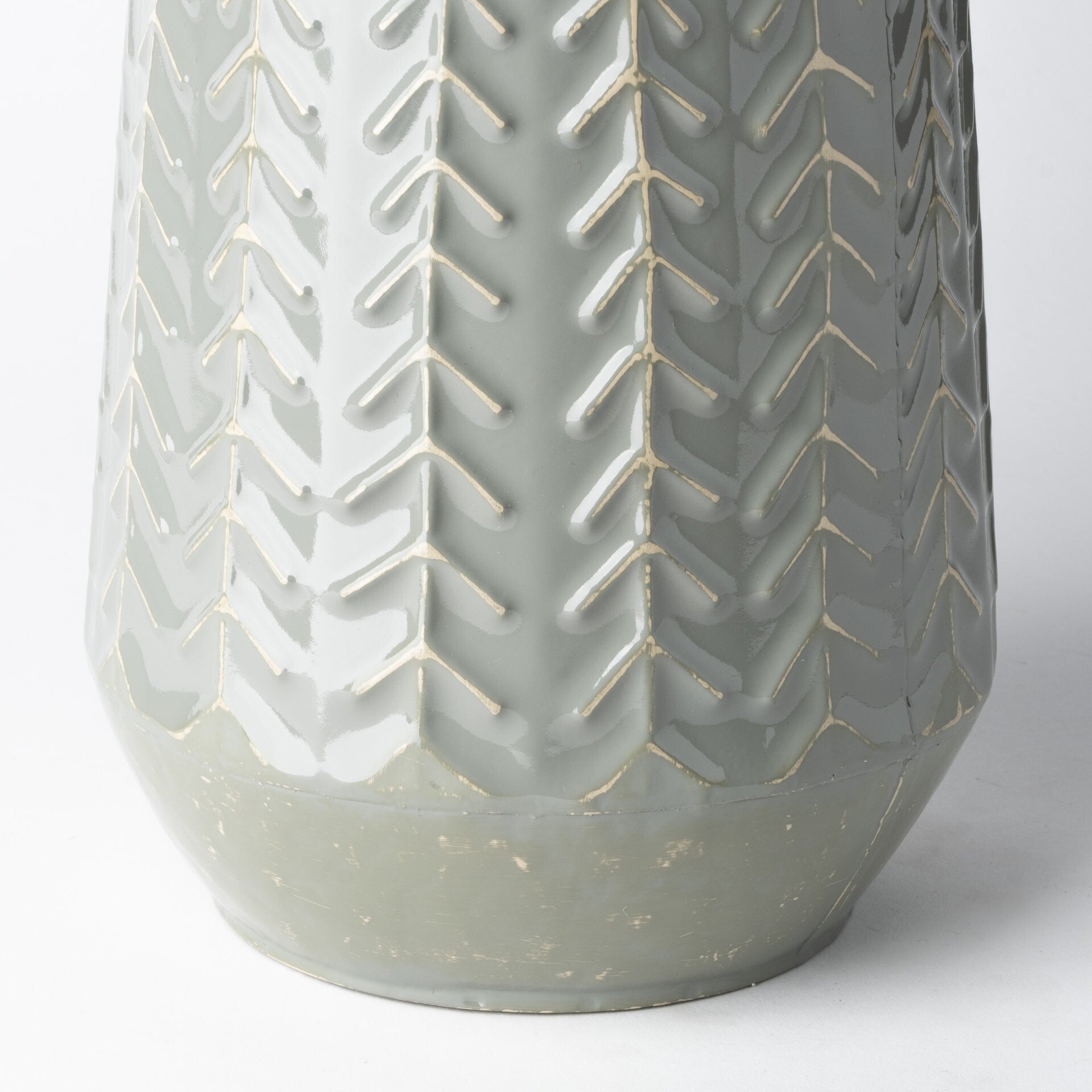 Embossed metal vase side view displaying chevron arrow pattern and solid metal construction
